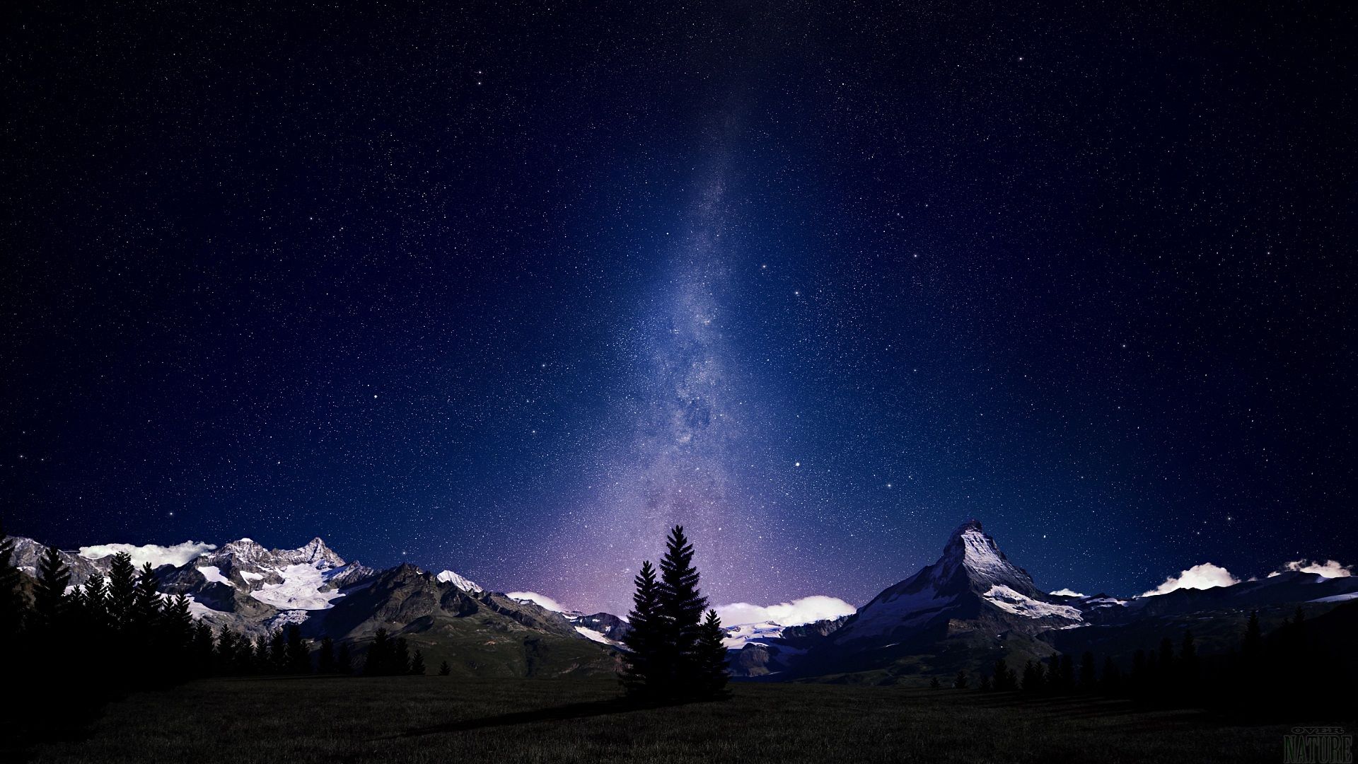 Paesaggio notturno con cielo stellato e la Via Lattea sopra cime innevate e sagome scure di pini