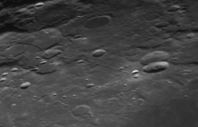 Primo piano in scala di grigi della superficie lunare con crateri e creste